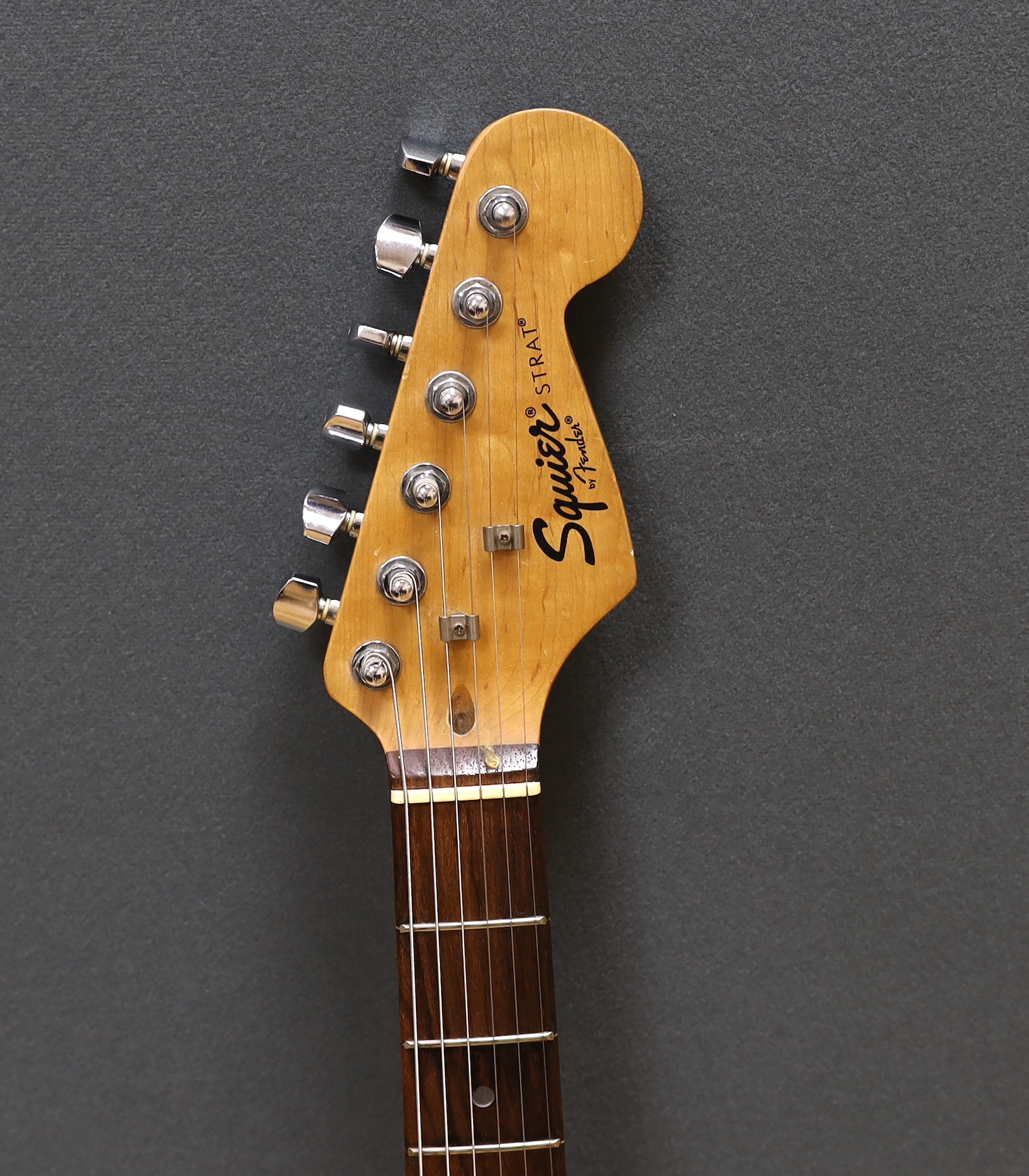 A cased Squier Strat by Fender electric guitar with rosewood neck and balance lacquer body, together with a Harris Tweed flight case